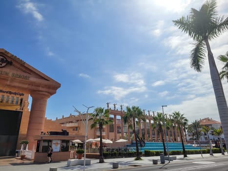 Hard Rock Cafe, Playa de la Americas, Tenerife, Spain August 12, 2022 - View from across the street of the Cafe building with palm trees and sky