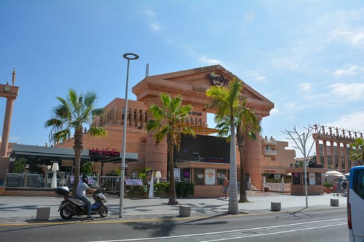 Hard Rock Cafe, Playa de la Americas, Tenerife, Spain August 12, 2022 - View from across the street of the Cafe building with a motorbike and palm trees and blue sky