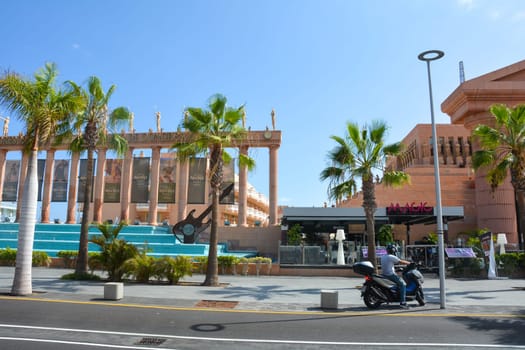 Hard Rock Cafe, Playa de la Americas, Tenerife, Spain August 12, 2022 - View from across the street of the Cafe building with a motorbike and palm trees and blue sky