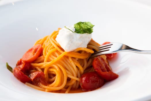 Italian pasta - spaghetti with burrata cheese closeup, mediterranean diet