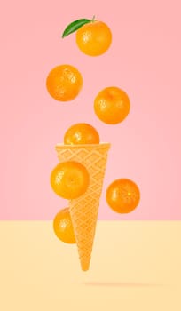 Isolated ice cream cone with fruits in the air. Seven falling whole tangerines on colored background with clipping path as package design element and advertising. Full depth of field.