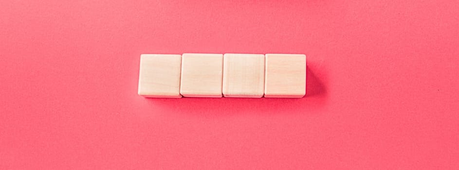 Wooden cubes isolated on pastel pink background with a place to insert text
