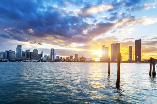 Miami city skyline panorama at dusk with urban skyscrapers over sea with reflection