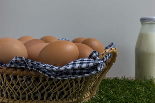 Basket contains group of chicken eggs put on grass.