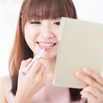 Portrait of attractive Asian girl putting lipstick on lips. Young woman living lifestyle.