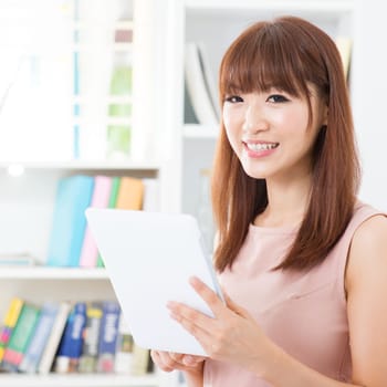 Portrait of attractive Asian girl using computer tablet. Young woman indoors living lifestyle at home.