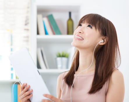 Portrait of attractive Asian girl listening to music and dancing with the beats. Young woman indoors living lifestyle at home.