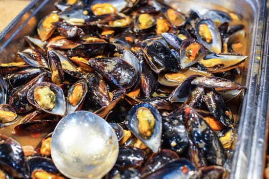 Black and yellow mussels at buffet restaurant, closeup detail.