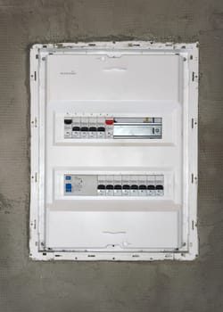 Box with electric switch fuses or circuit breakers installed on bare wall in new house construction site.