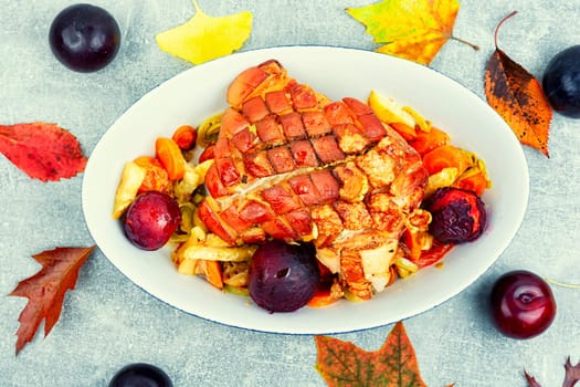 Juicy pork shoulder with skin and bacon cooked with vegetables and plums. Copy space