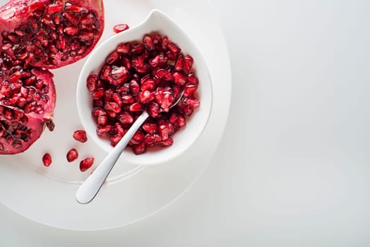Healthy ripe pomegranate fruit opened and splited with seeds on white plate