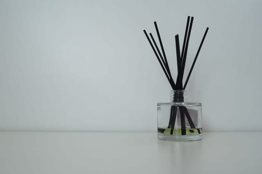 Incense sticks are lowered into a glass cubic vessel with essential oils. Interior decor. White background. Still life with sticks to create a pleasant smell in the room