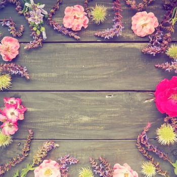Flowers in a circle on a wooden background. Postcard for the holiday. Roses, geraniums, lavender, sage and hairy chestnuts are placed along the edges on dark boards. Background copy space, flat lay