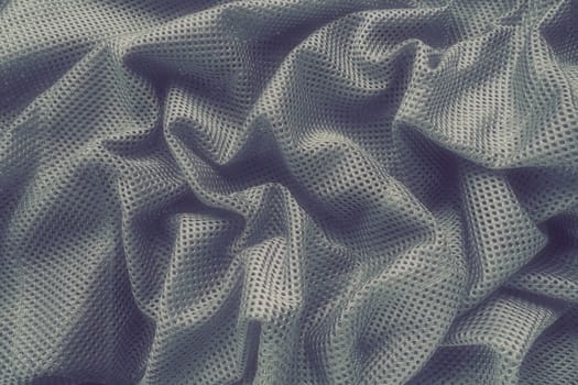 Synthetic fabric with holes laid in waves. Beautiful drape. Fabric for curtains, interior design, and decor. Wrinkled gray fabric