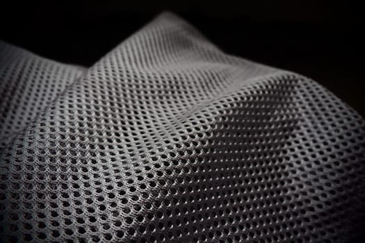 Synthetic fabric with holes laid in waves. Beautiful drape. Fabric for curtains, interior design, and decor. Wrinkled gray fabric