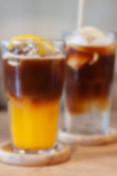 Glass of americano mixed with orange juice blur background, stock photo