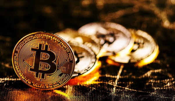 Closeup of golden bitcoin BTC cryptocurrency over black and gold background. Virtual money and blockchain concept.