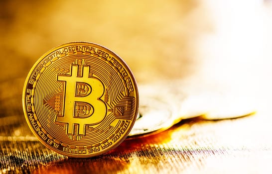 Closeup of golden bitcoin BTC cryptocurrency over black and gold background. Virtual money and blockchain concept.