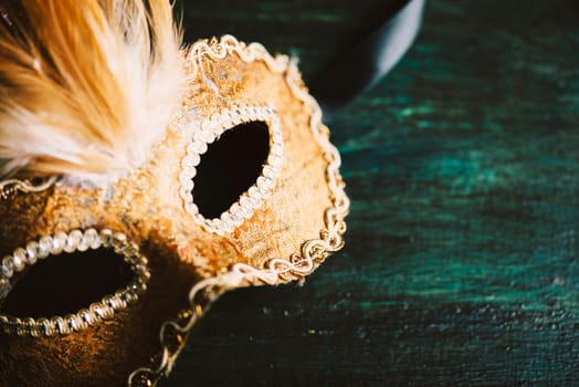 Golden venetian ball mask over dark background with copyspace. Masquerade party or holiday event celebration concept.