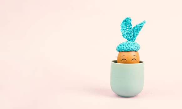 Cute easter bunny or rabbit with a smiling egg face in a cup, spring holiday, greeting card