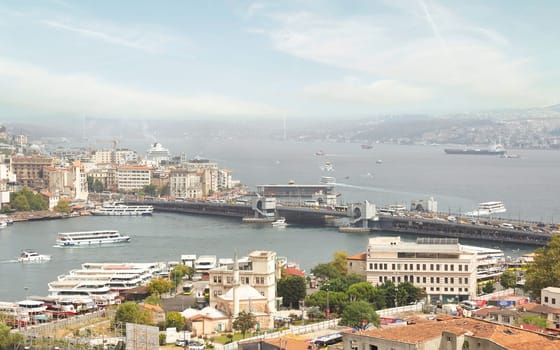 Aerial view of Golden Horn, with Galata Bridge and Karakoy Ferry Terminal with ferry boat approaching the terminal, and Bosphorus bridge in the far end, Istanbul, Turkey