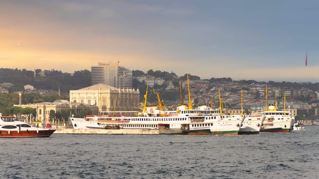 View of the European coast of the Bosporus strait in Besiktas district with docked ferry boats, and Dolmabahce Palace in the background, Istanbul, Turkey