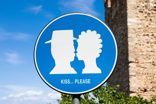 Kiss street sign located in public area in front of Sirmione castle, Italy. Concept of love, couple, romantic