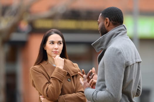 Suspicious woman listening a man talking in the street in winter