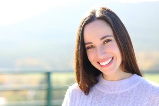 Portrait of a happy woman with white tooth standing in nature looking at camera