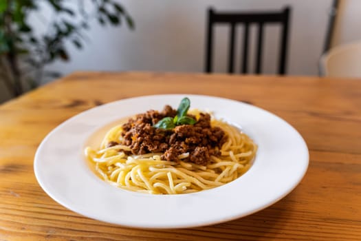 Plate with traditional Italian pasta spaghetti bolognese on a wooden table in the restaurant