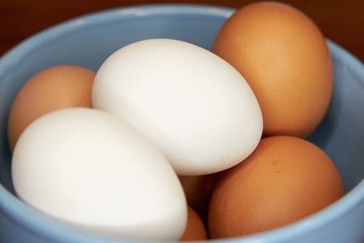 fresh brown and white eggs in a bowl on a kitchen table