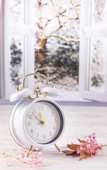Vintage alarm clock on table with open window, winter time