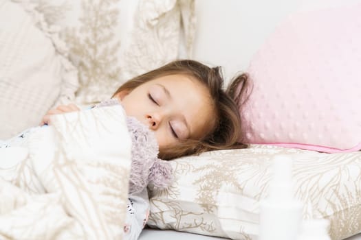 Nice little girl sleeping on bed under blanket with teddy bear. Portrait of asleep child. Morning, have sweet dream. Sleep with favorite stuffed toy. Resting in bedroom, cozy bedclothes.