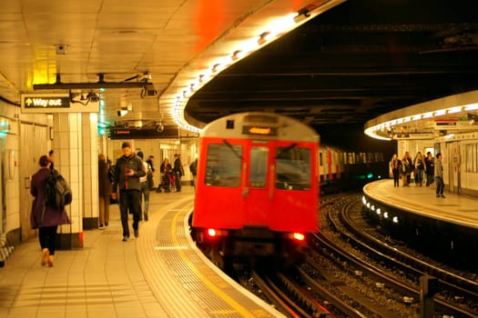 London,United Kingdom - March 31,2015: A subway enters a bend at a metro station where people wait for the train on March 31,2015 in London.