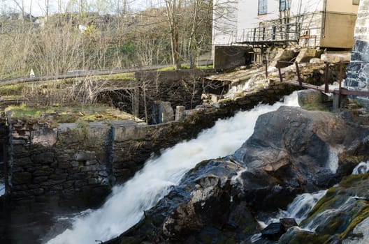 the water is rushing down and it s milky and the house in the background