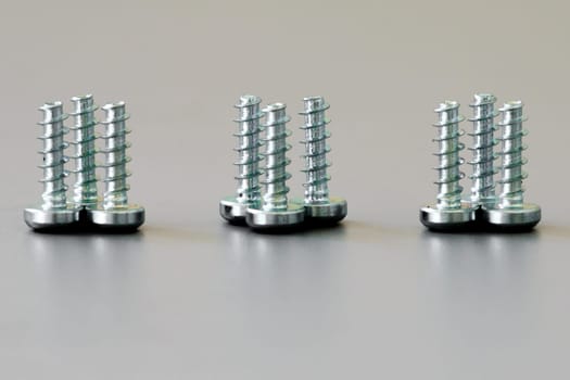 A close up of nine threaded screws standing side by side