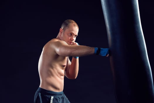 Young boxer boxing over  the black background