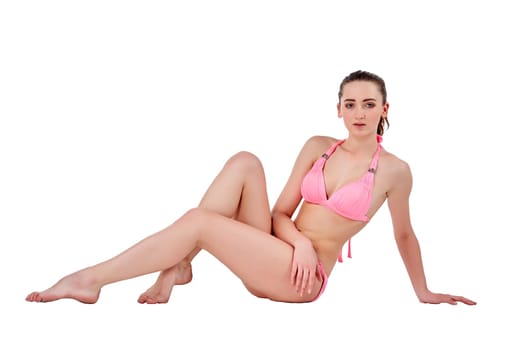 Beautiful young brunette  woman in pink swimwear sitting and isolated on white background