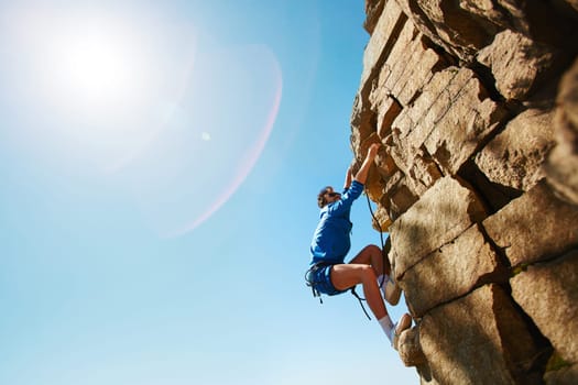 Young man climbing on top of rock