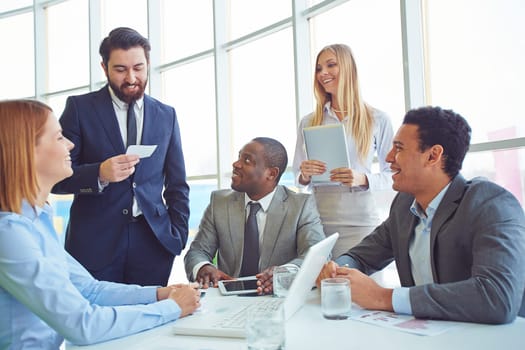 Happy colleagues listening to elegant employee at meeting