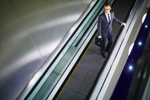 Attractive businessman moving on escalator