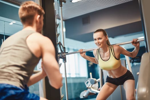 Sporty female looking at her trainer during weightlifting workout