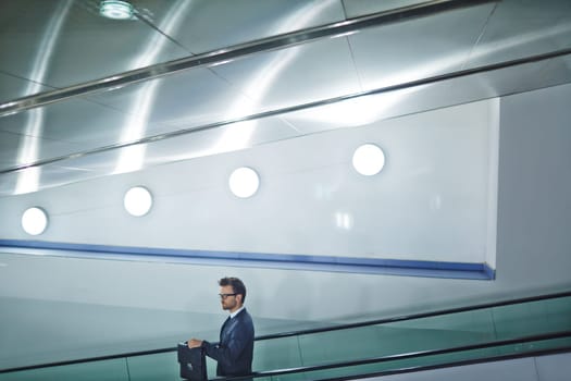 Business agent with briefcase descending on escalator