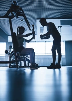 Outlines of female exercising on facilities and her trainer