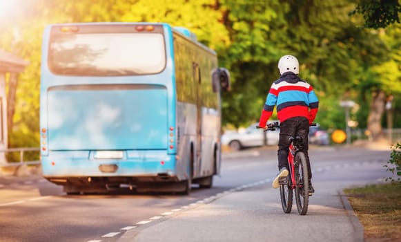 Boy on a bicycle trying to catch up with a blue bus. Concept of the teaching a child the rules of the road and back to school.