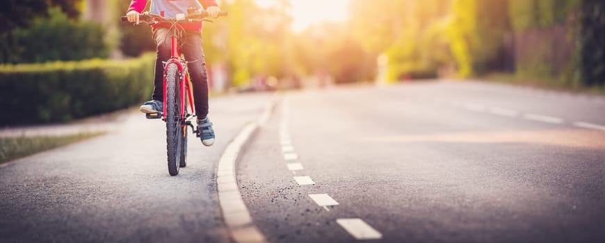 Boy riding a bike on the sidewalk along asphalt road. Concept of learning to drive a bike and independence.