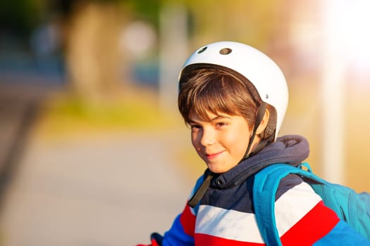Cute boy in helmet standing and smiling at photocamera. Concept of biking, cycling and driving safety.
