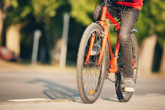 Boy riding a bike on the sidewalk along asphalt road. Concept of learning to drive a bicycle and independence.