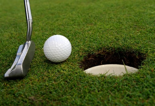 Golf hole with ball and club on green