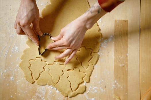 Top view of female hand cutting out biscuits from dough with cookie cutter